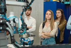 Students watch a robotic arm manufacturing machine