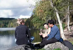 Three students sitting by a lake